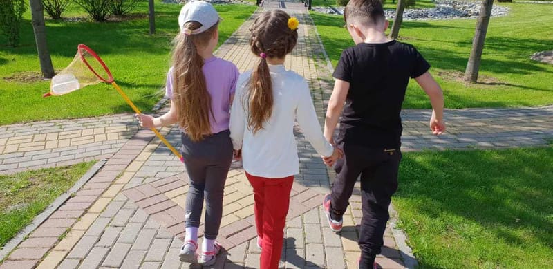 Дети и преподаватель идут по территории школы на прогулке