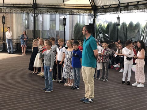 Преподаватель и группа младших детей на сцене концерта
