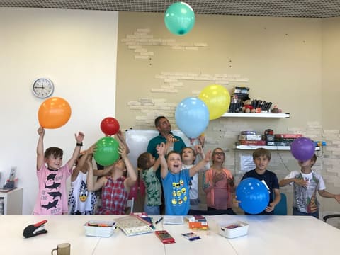 Группа младших детей с воздушными шарами в классе