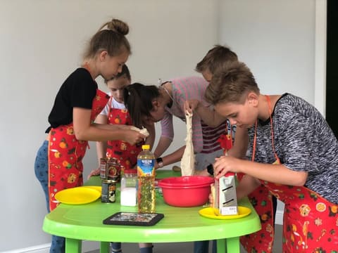 Дети в фартуках готовят за столом на кулинарном занятии
