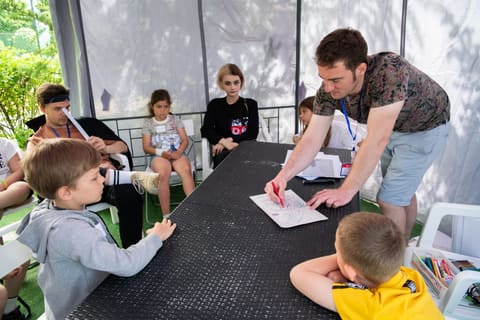 Занятие под белым шатром: преподаватель показывает задание