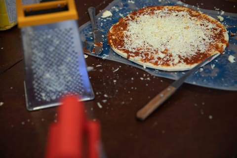 Готовая пицца с сыром и тёрка на столе кулинарного класса
