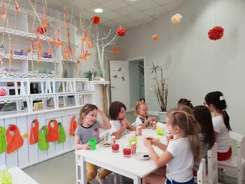 Дети за столами в игровой комнате детского сада