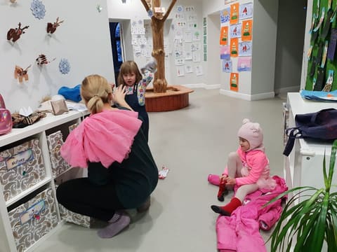 Воспитатель помогает детям одеться на прогулку